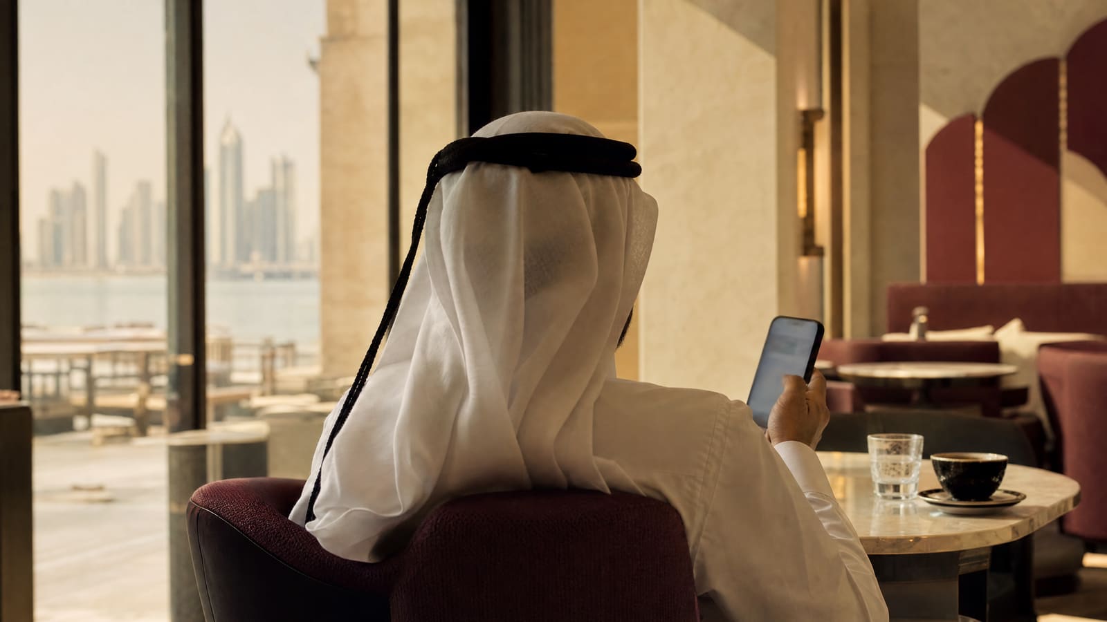 Business owner reviewing enquiries on a phone in a modern café in Doha